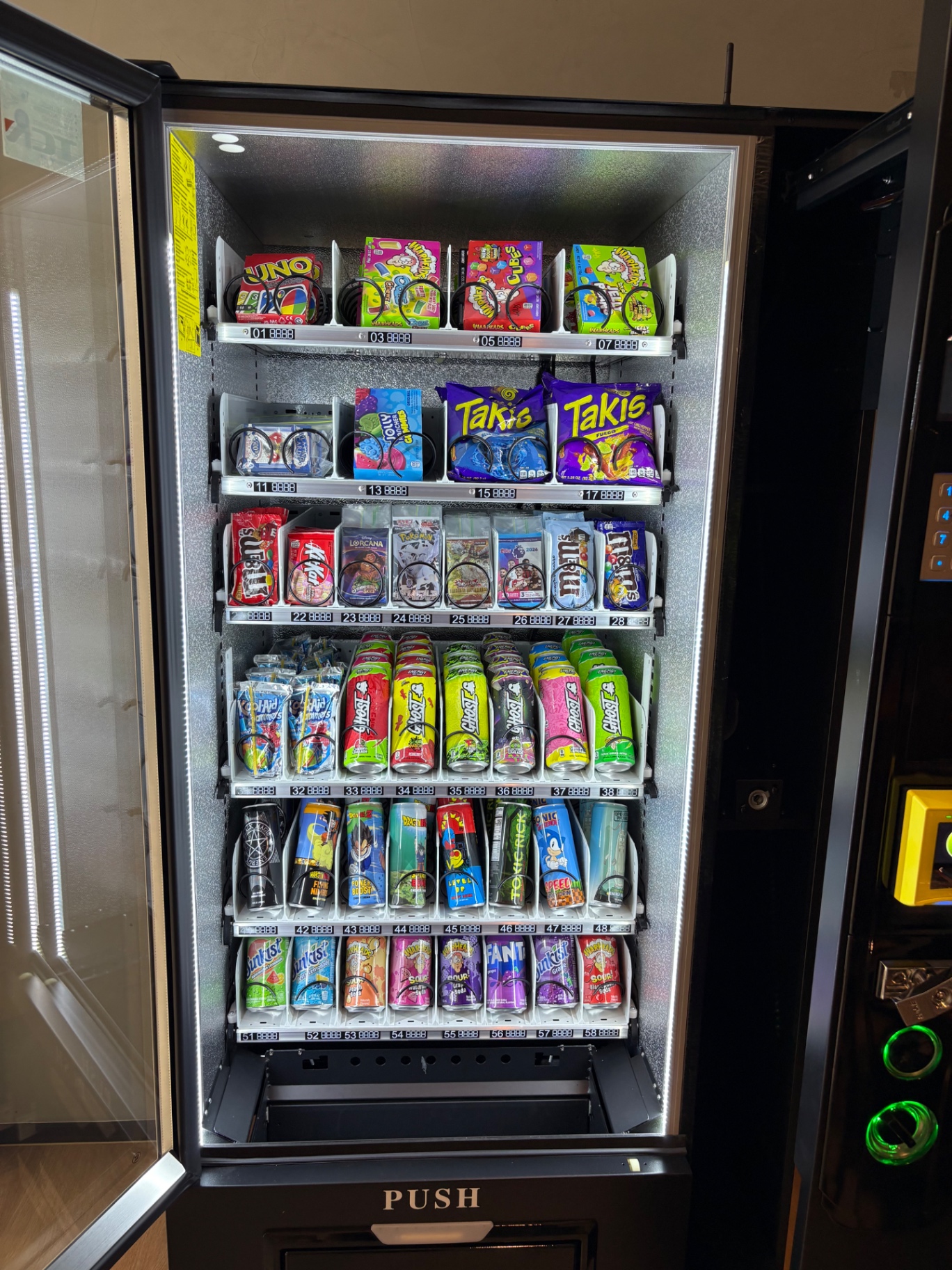 Gaming vending machine stocked with colourful snacks, drinks and Pokémon trading cards